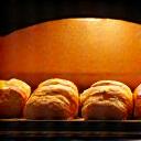 A tray of bread loaves baking inside a professional deck oven.
